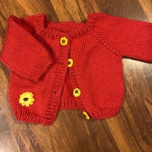Pink knit cardigan with sunflower buttons.